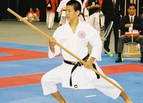 Man in white gi holding wooden staff
