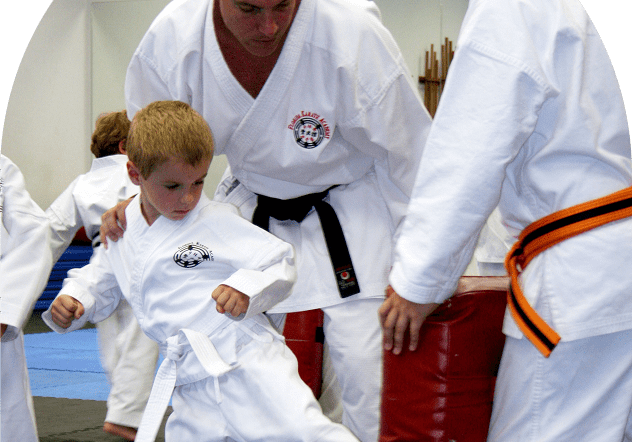 Child practicing karate kick with instructor